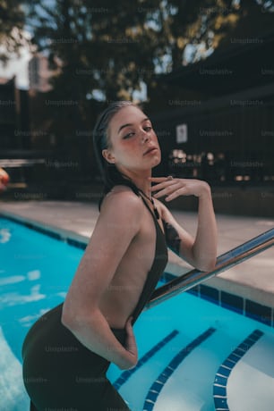 a woman leaning against a railing next to a swimming pool