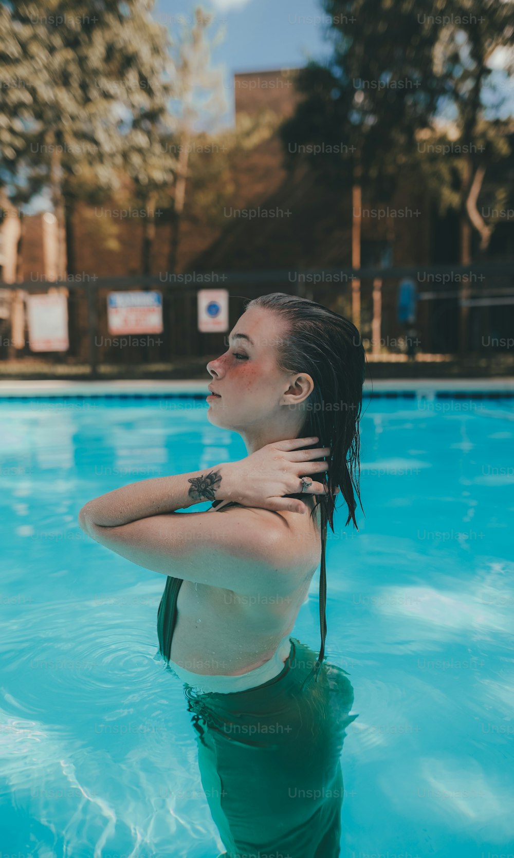 a woman standing in a pool with her arms behind her back
