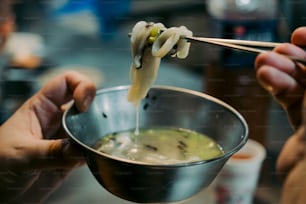 スープのボウルの上に箸を持っている人