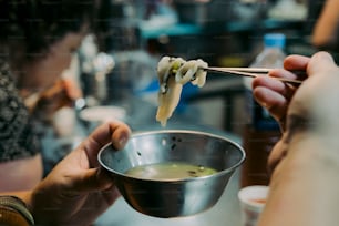 a person holding a bowl of food with chopsticks