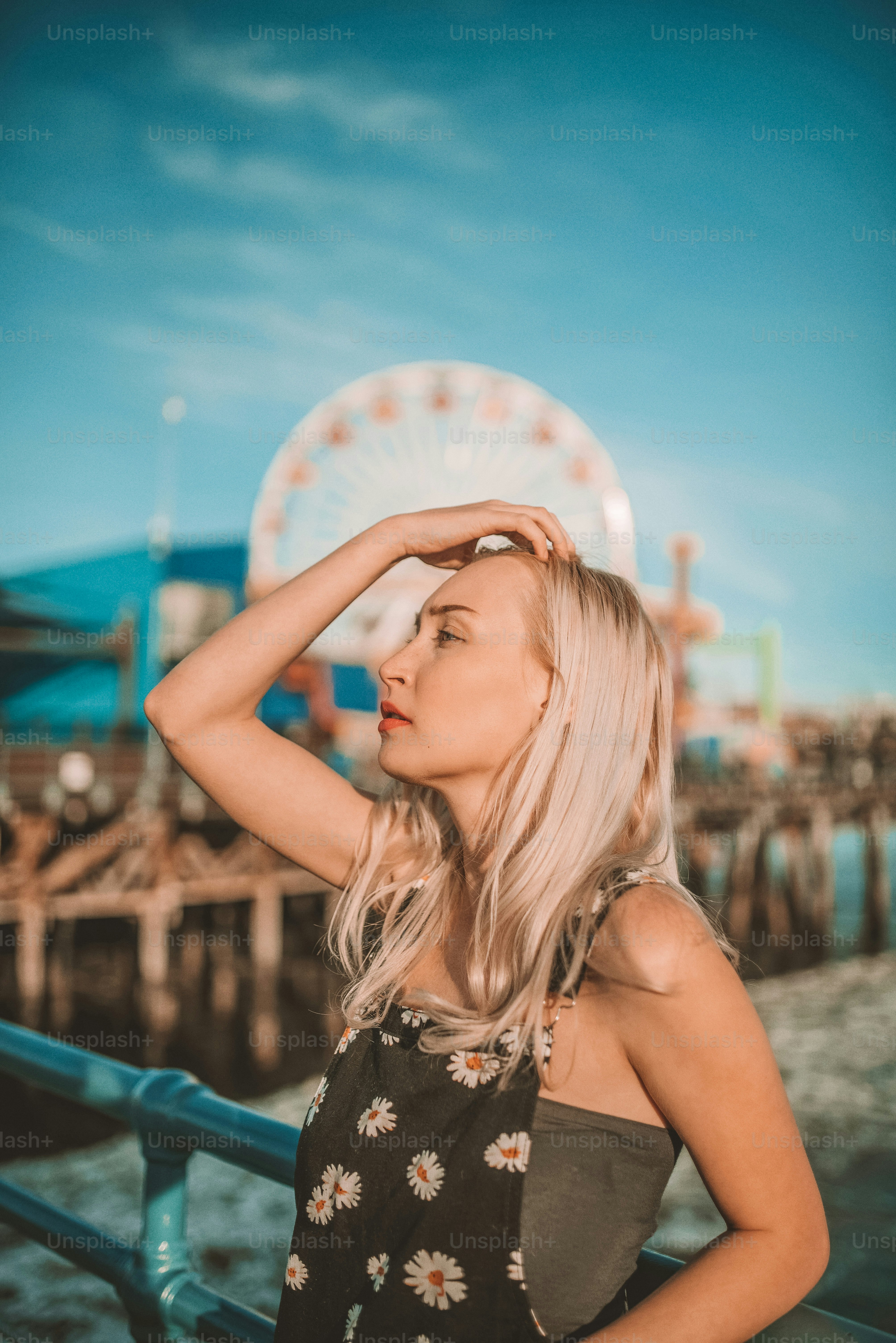 a woman standing on a pier next to a ferris wheel