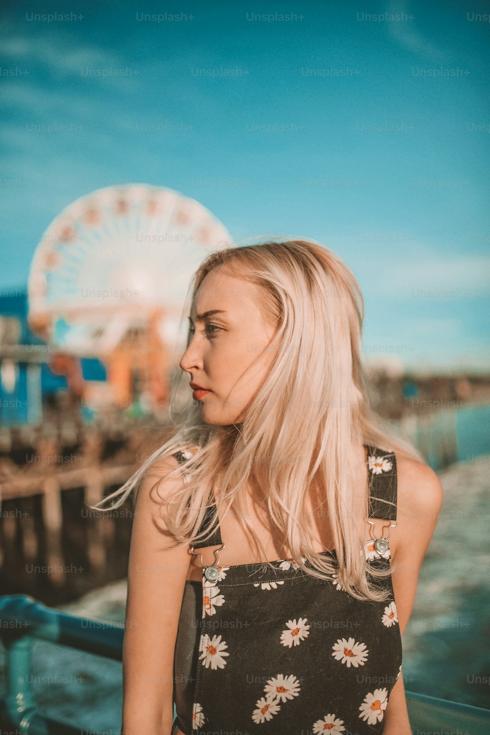 a woman standing on a pier next to a ferris wheel