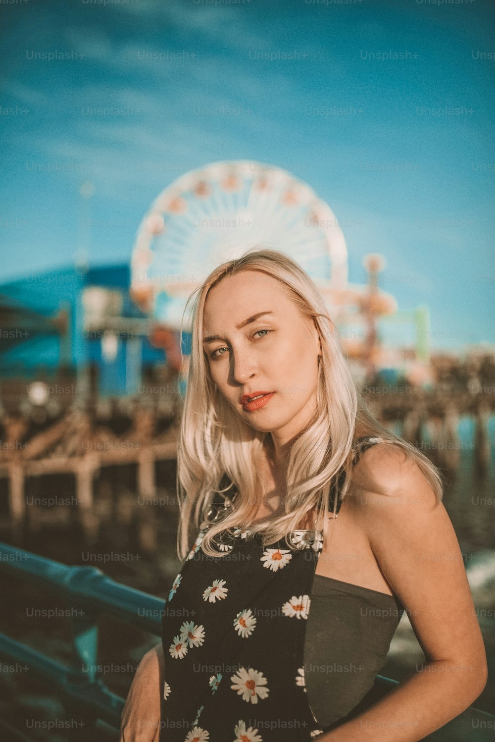 a woman with blonde hair standing in front of a ferris wheel