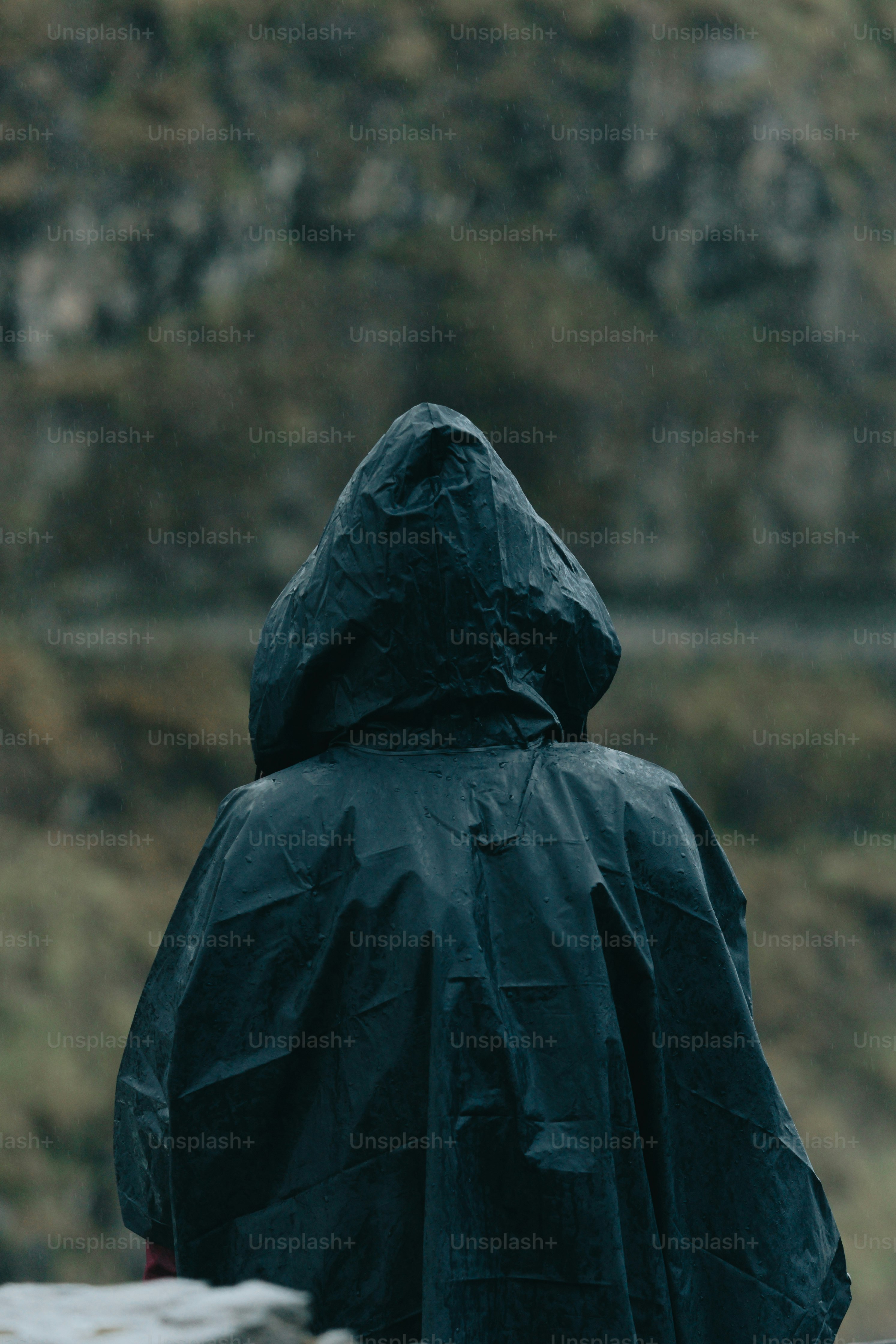 a person in a black raincoat is standing outside