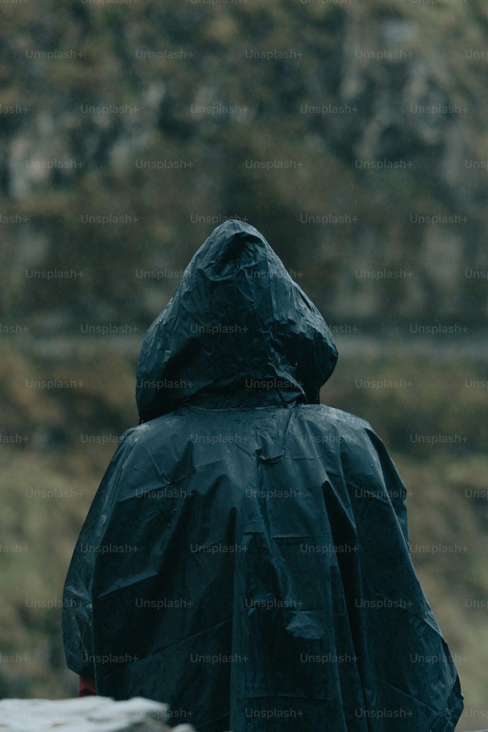 Eine Person in einem schwarzen Regenmantel steht draußen