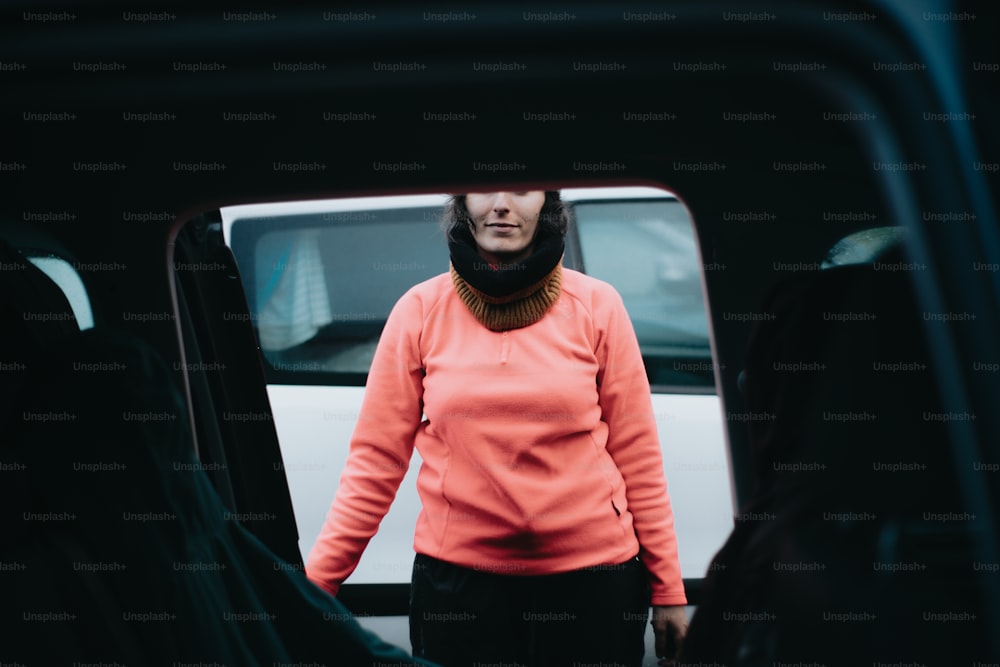 a woman in an orange shirt standing in front of a van