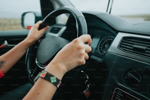 a person driving a car with their hand on the steering wheel