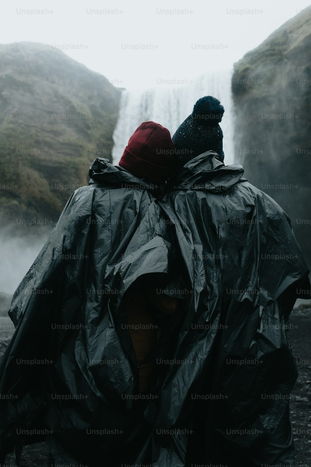 a couple of people standing next to a waterfall
