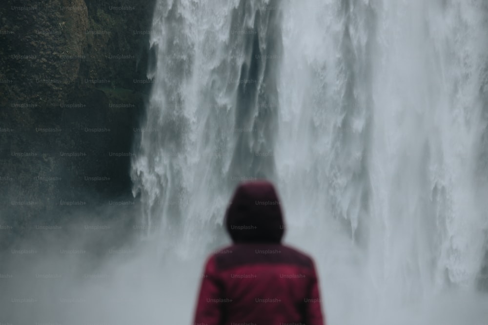 uma pessoa em pé na frente de uma cachoeira