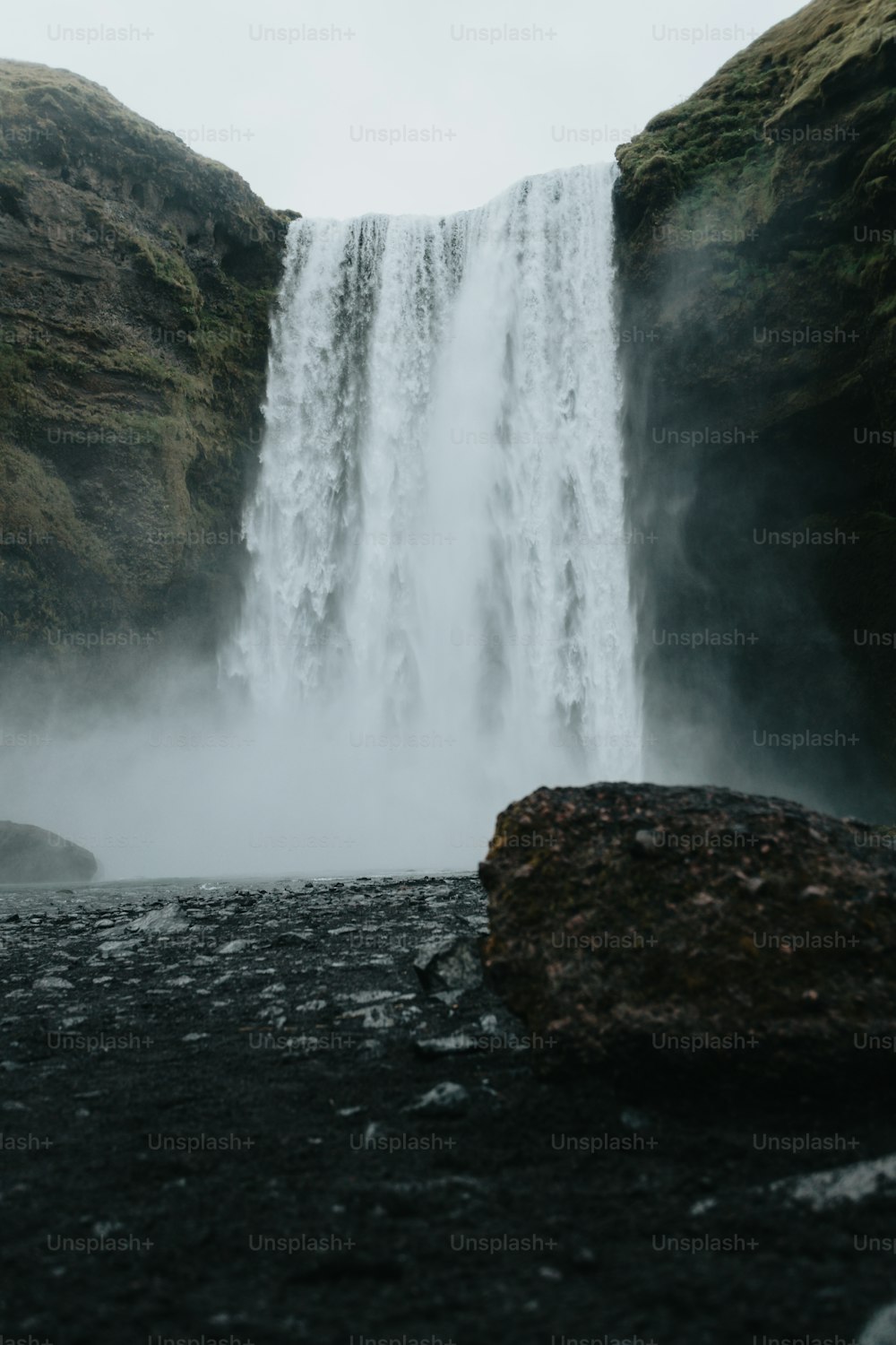 Ein großer Wasserfall mit einem großen Felsen davor