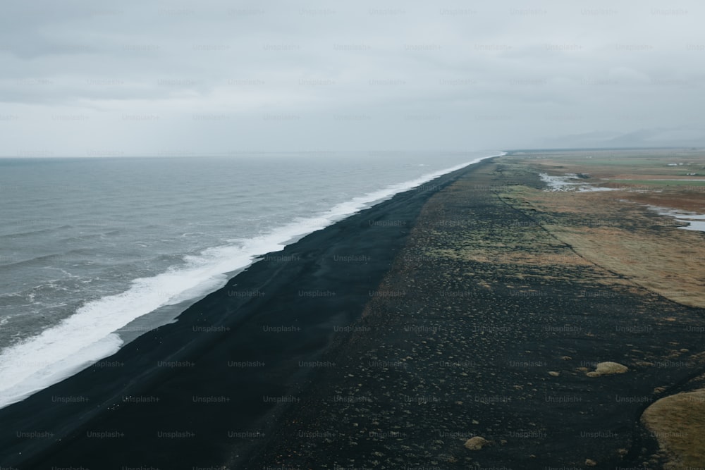 Ein langer schwarzer Sandstreifen neben dem Meer