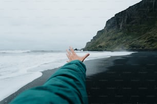 La mano di una persona che tende verso l'oceano