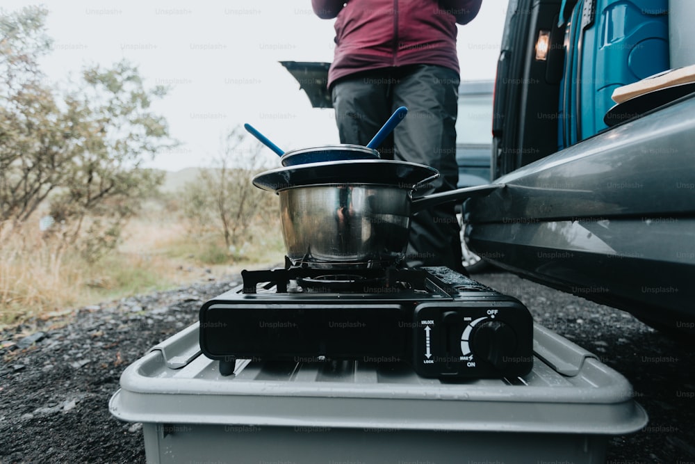 a person standing next to a truck with a pot on the stove