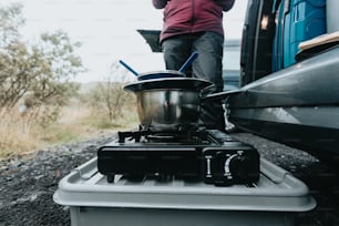 a person standing next to a truck with a pot on the stove