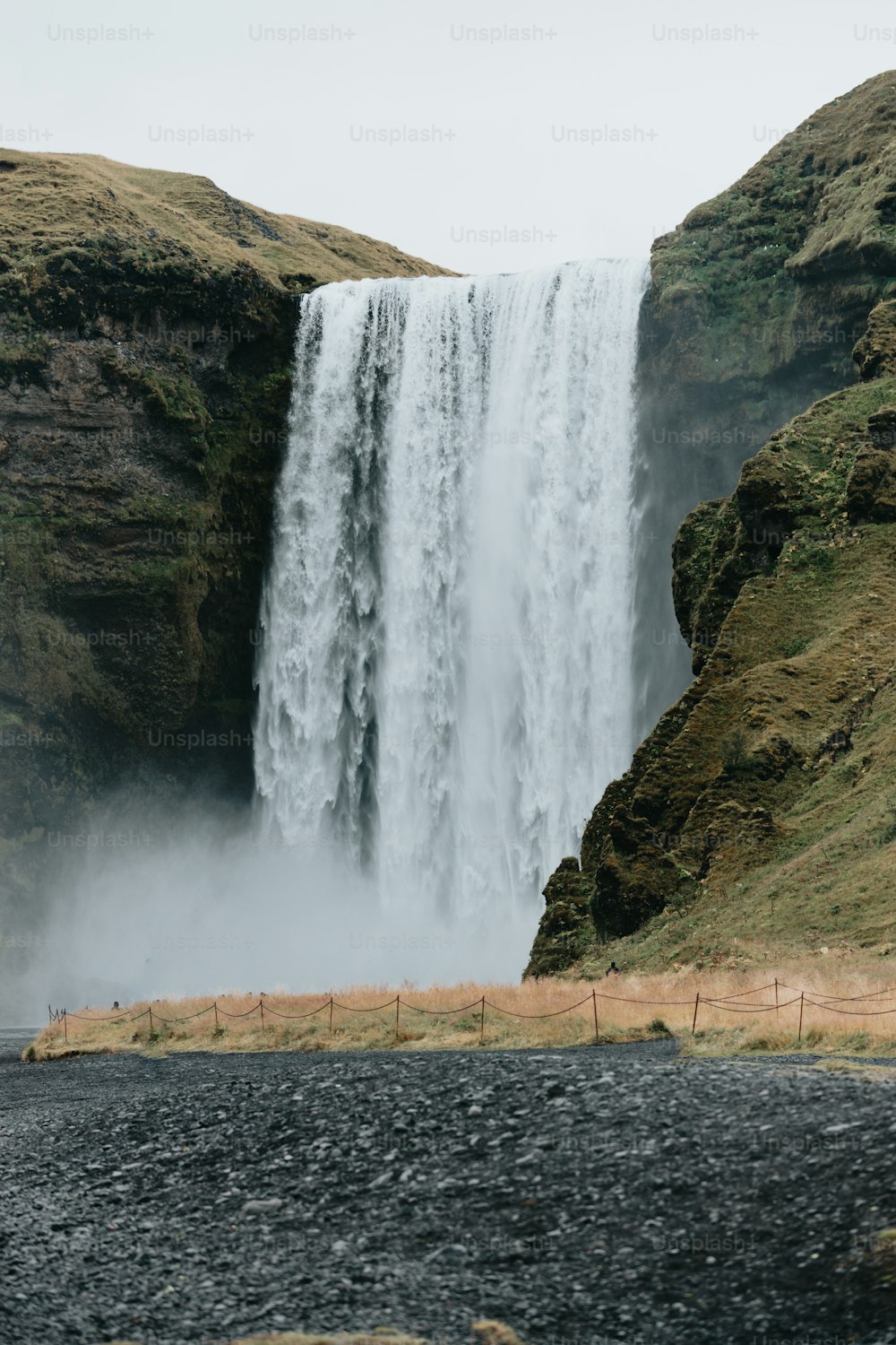 a large waterfall with a man standing in front of it