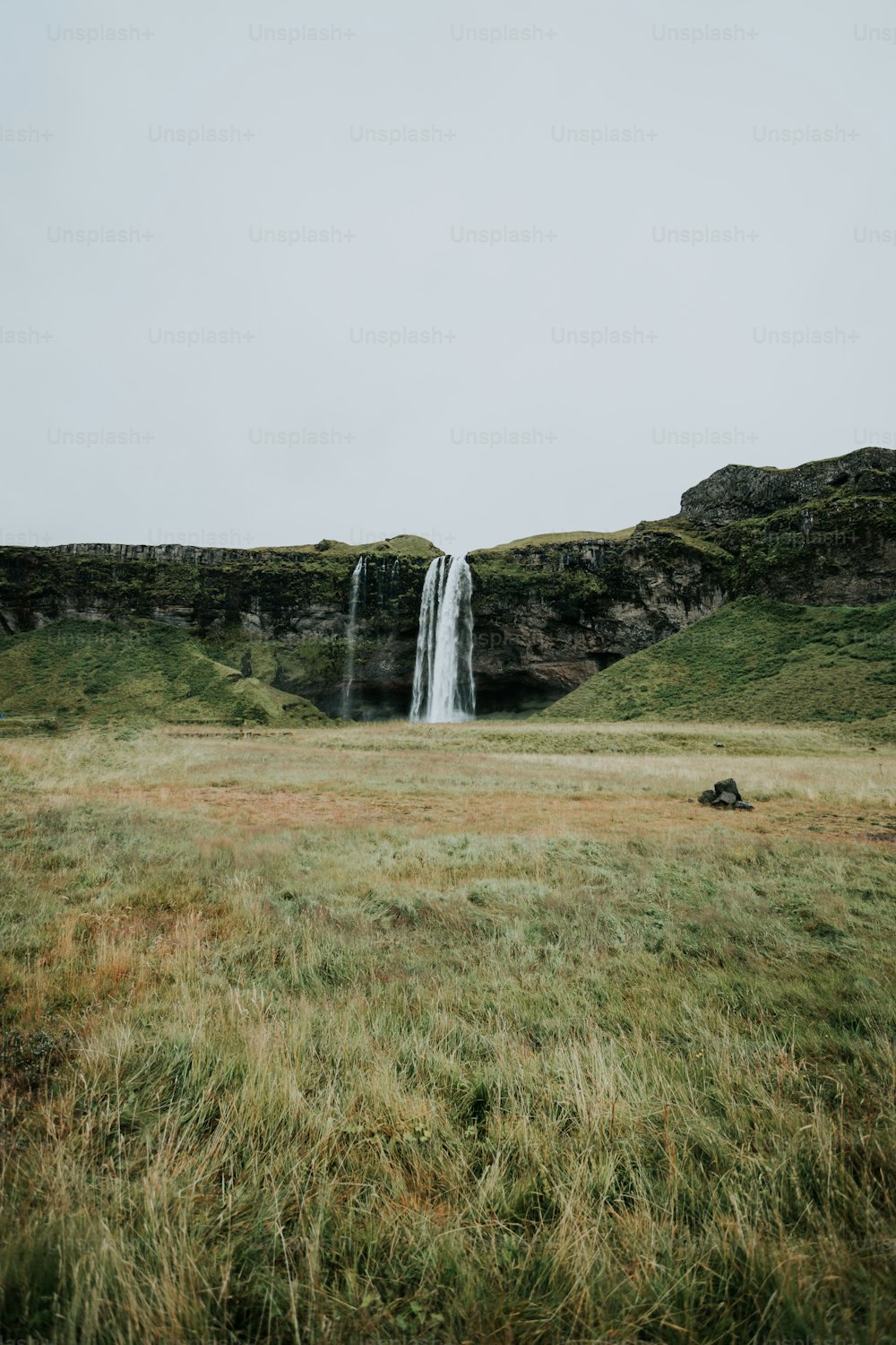 a waterfall in the middle of a grassy field