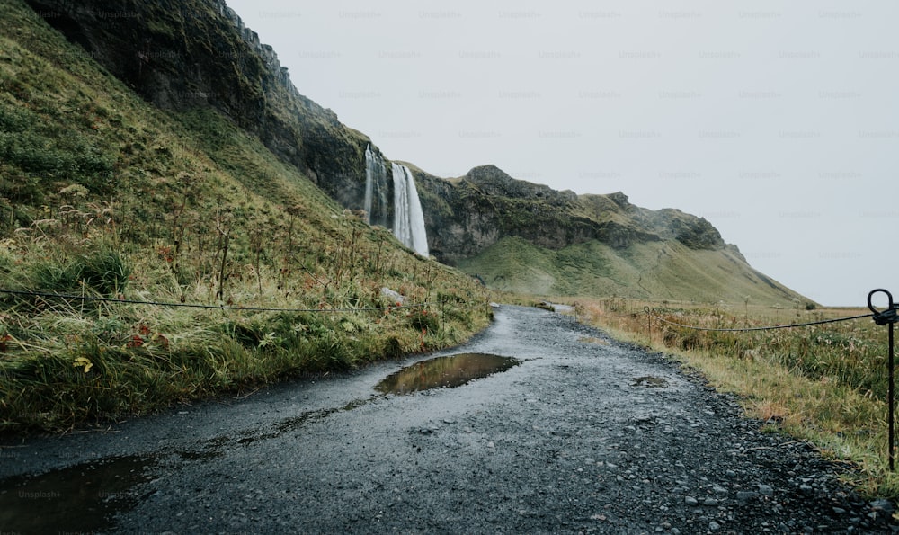 a narrow road with a waterfall in the background