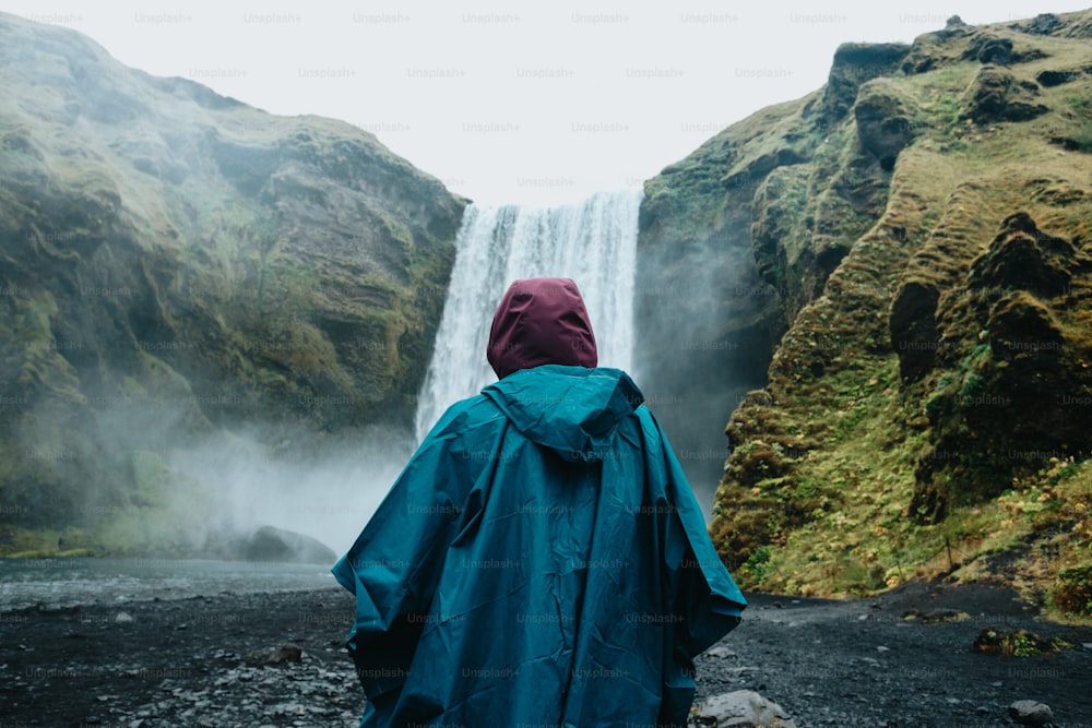 una persona in piedi di fronte a una cascata