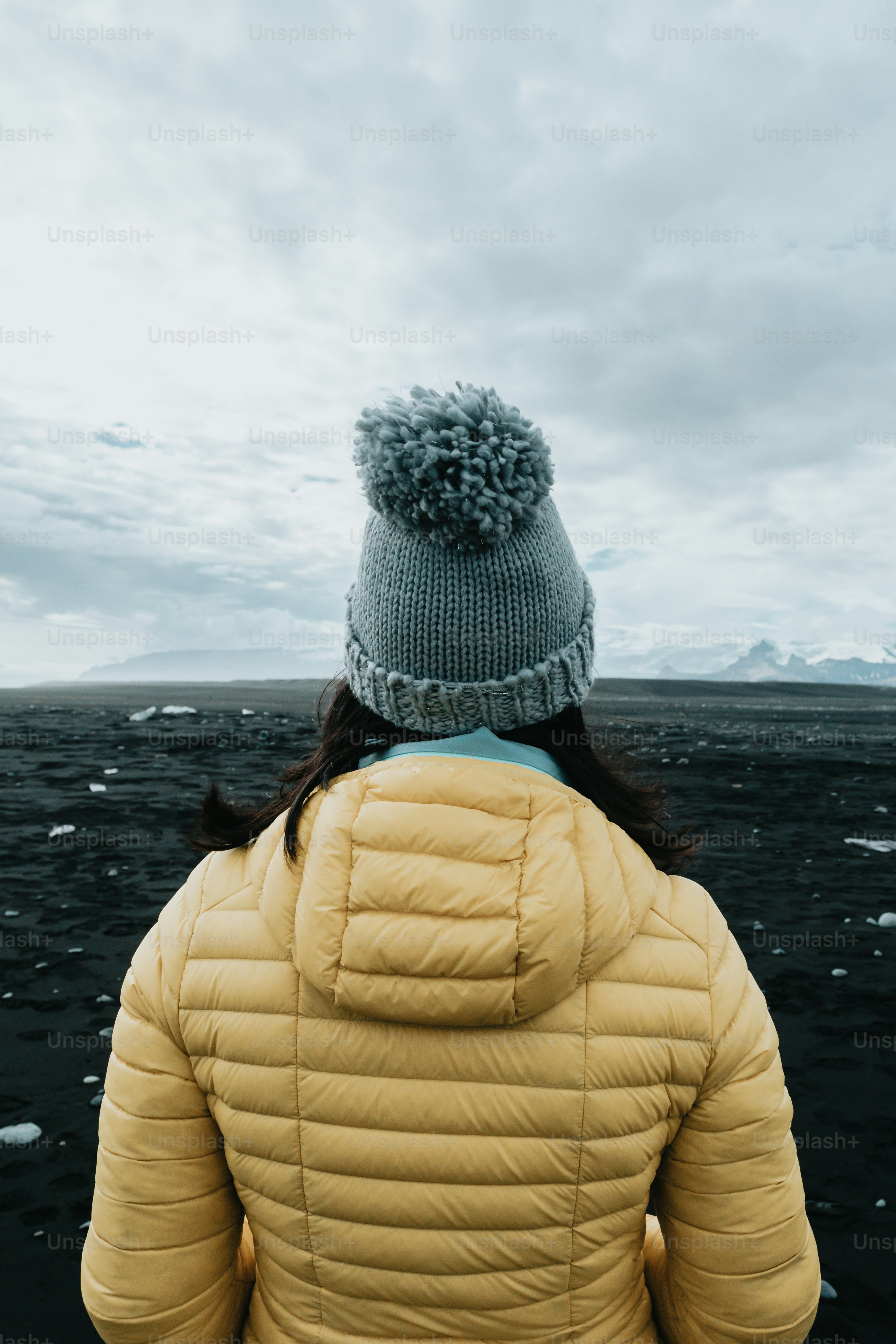 a woman in a yellow jacket looking out at the ocean