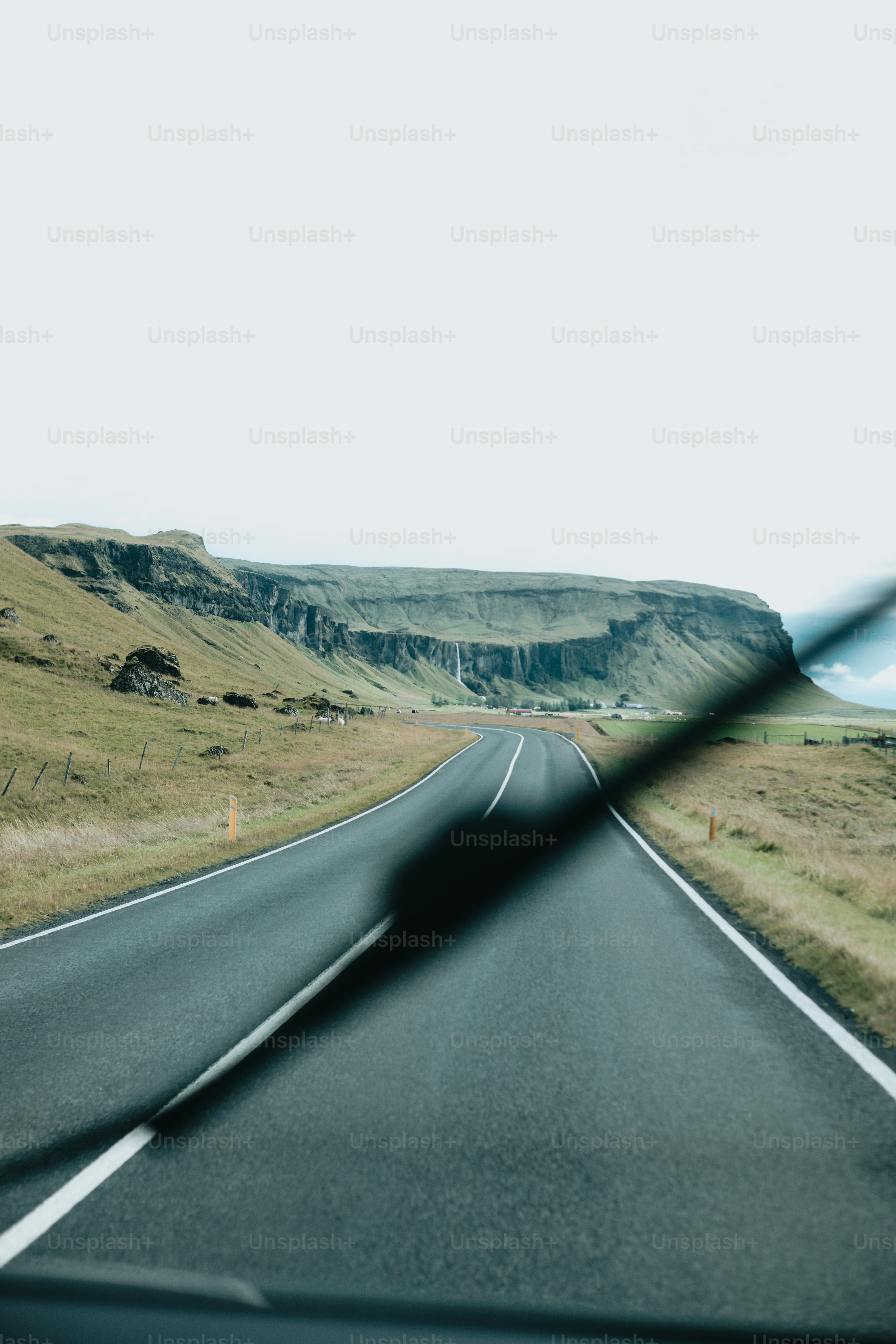 a car driving down a road next to a lush green hillside