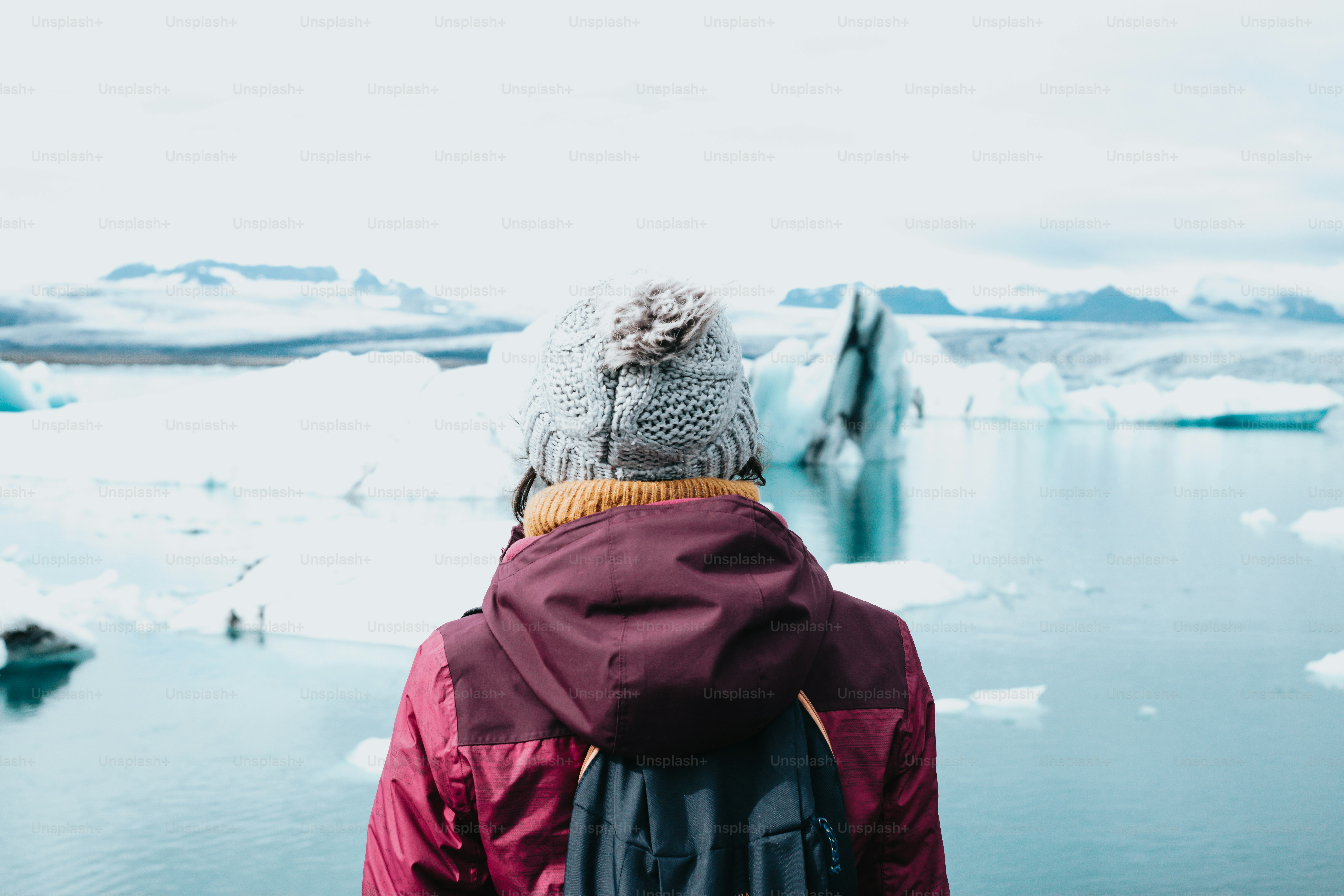 a person wearing a hat standing in front of a body of water