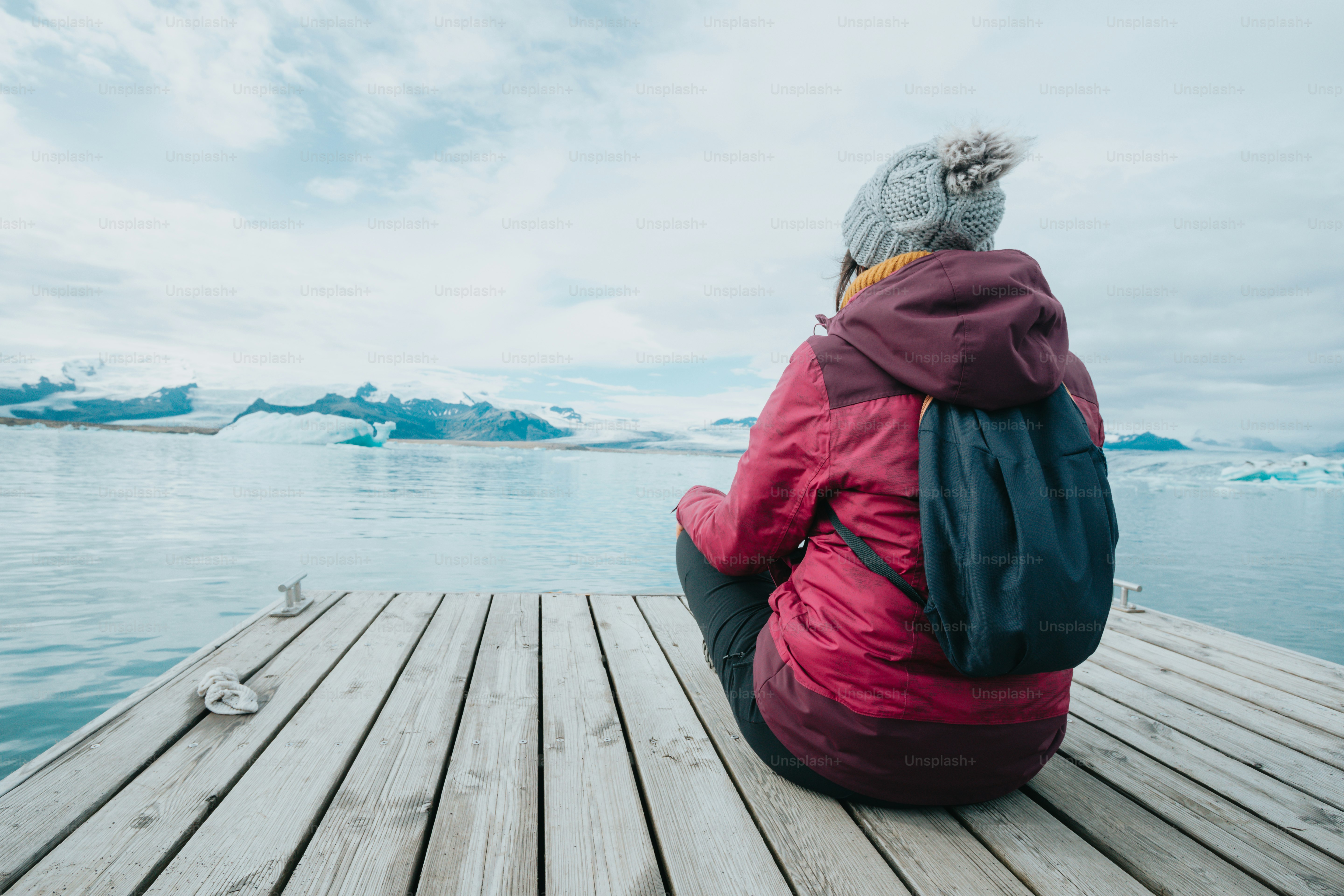 A woman sitting on a dock looking at the water photo – Exclusion Image ...
