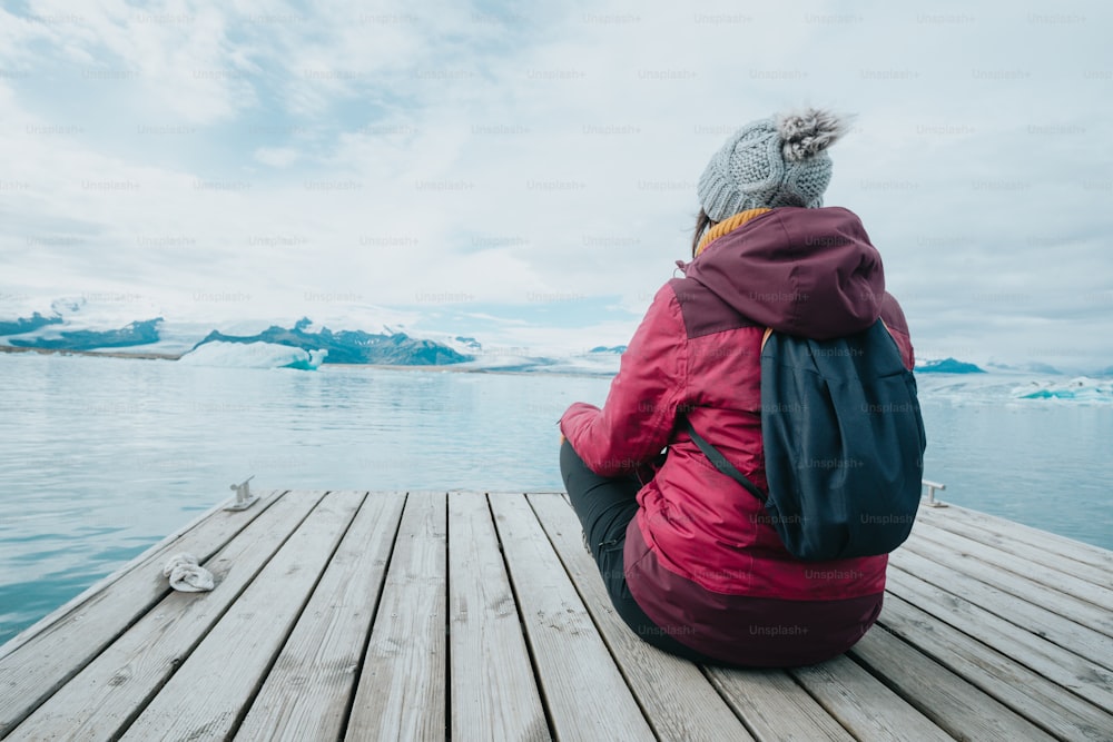 Eine Person, die auf einem Dock sitzt und auf das Wasser schaut