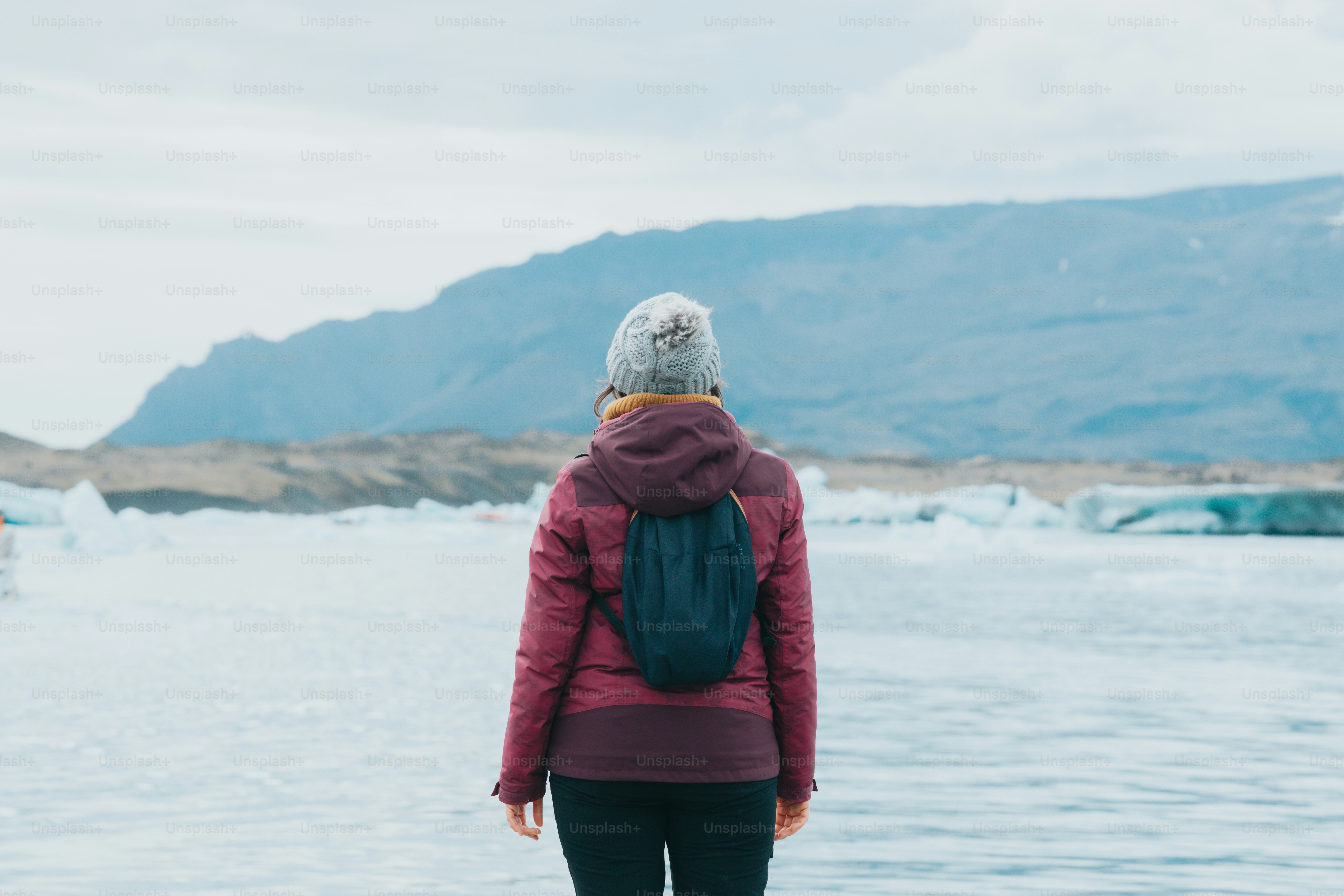 a woman in a red jacket is standing by the water