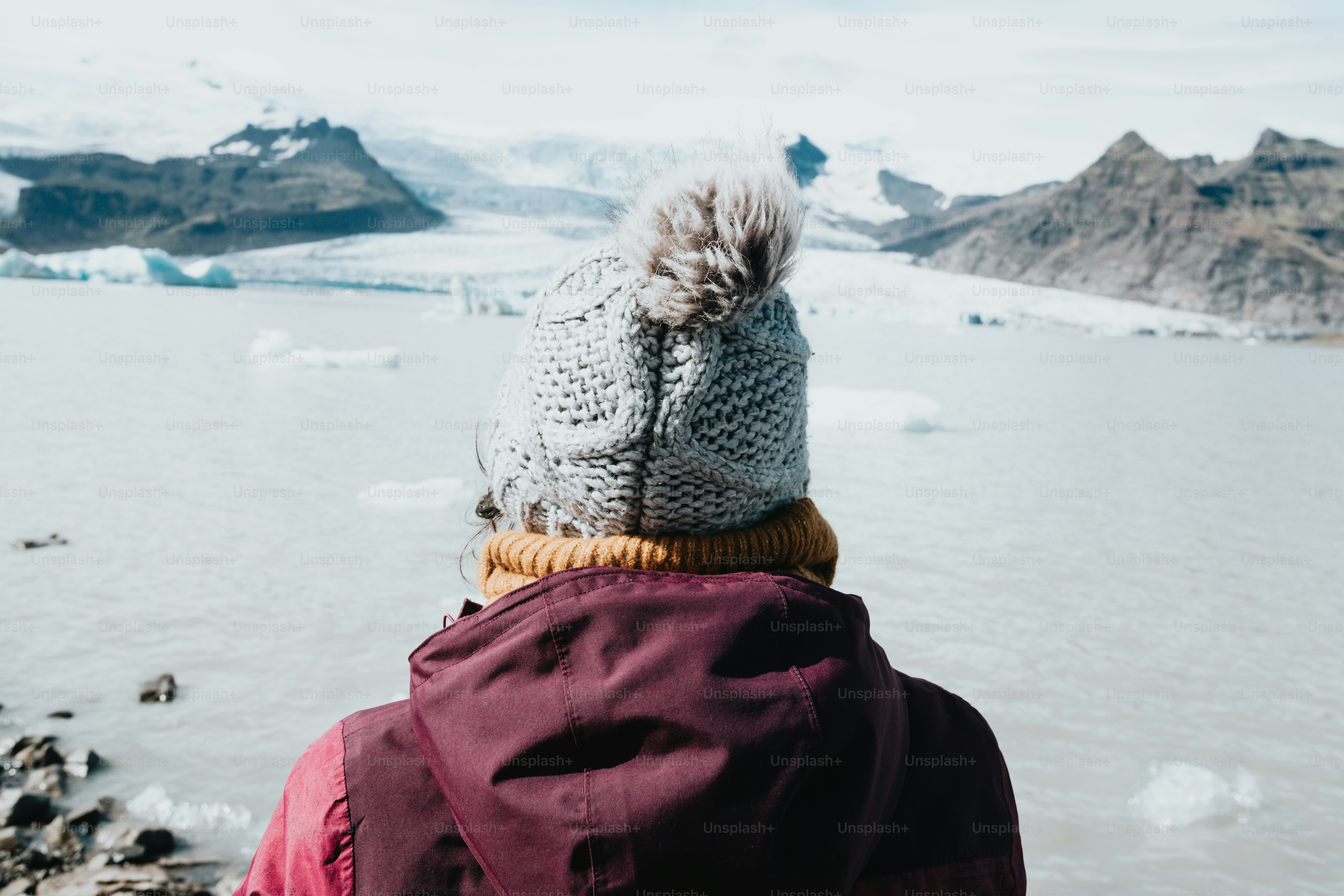 une personne portant un chapeau tricoté regardant au-dessus d’un plan d’eau