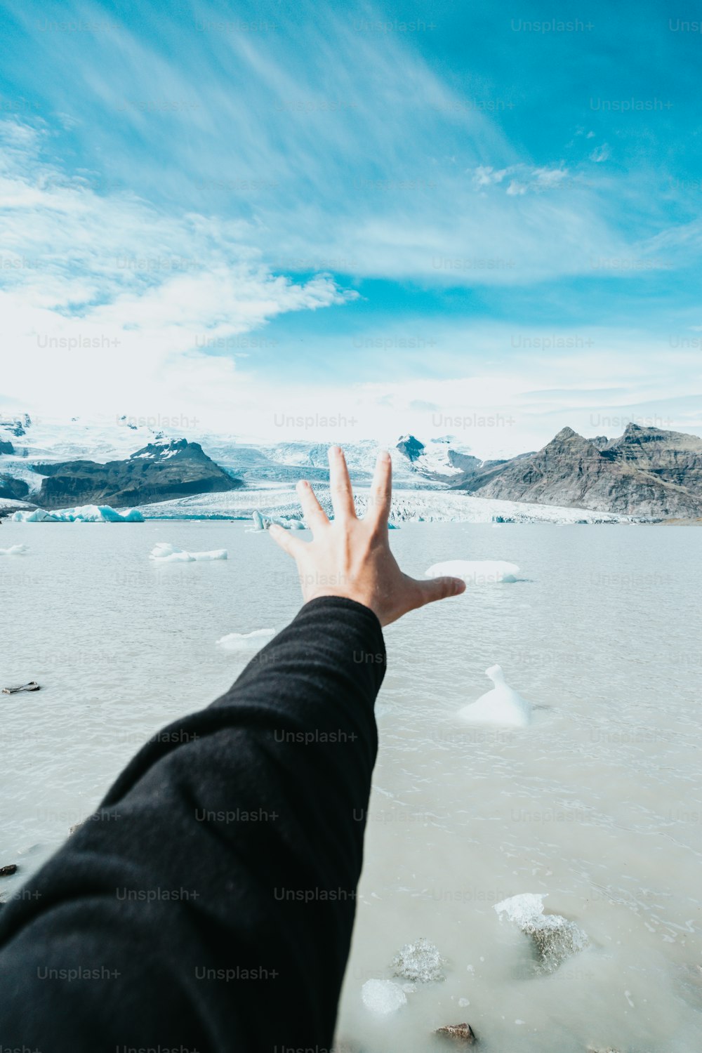 a person's hand reaching out towards a glacier