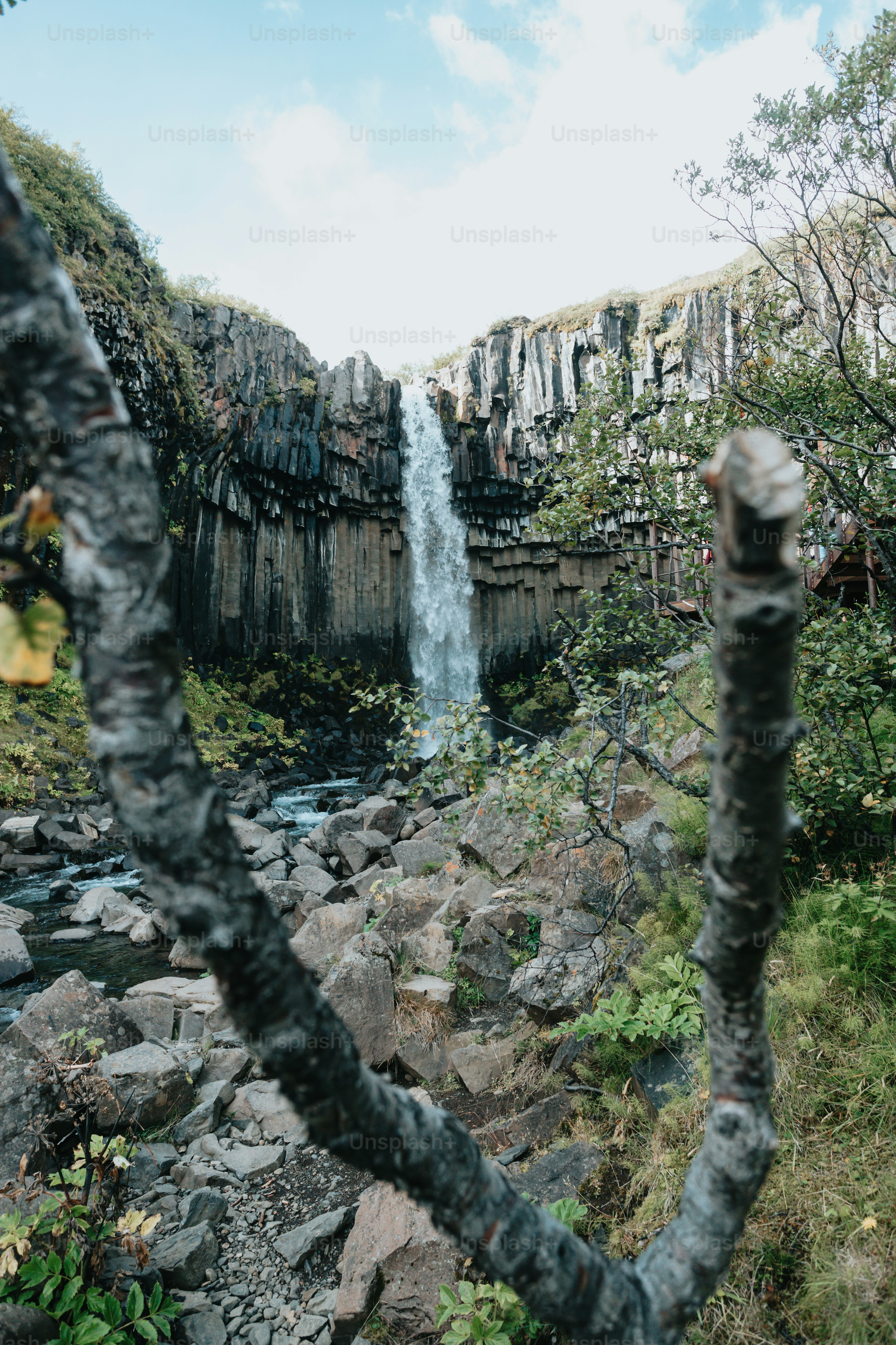 A view of a waterfall from behind some rocks photo – Travel Image on ...