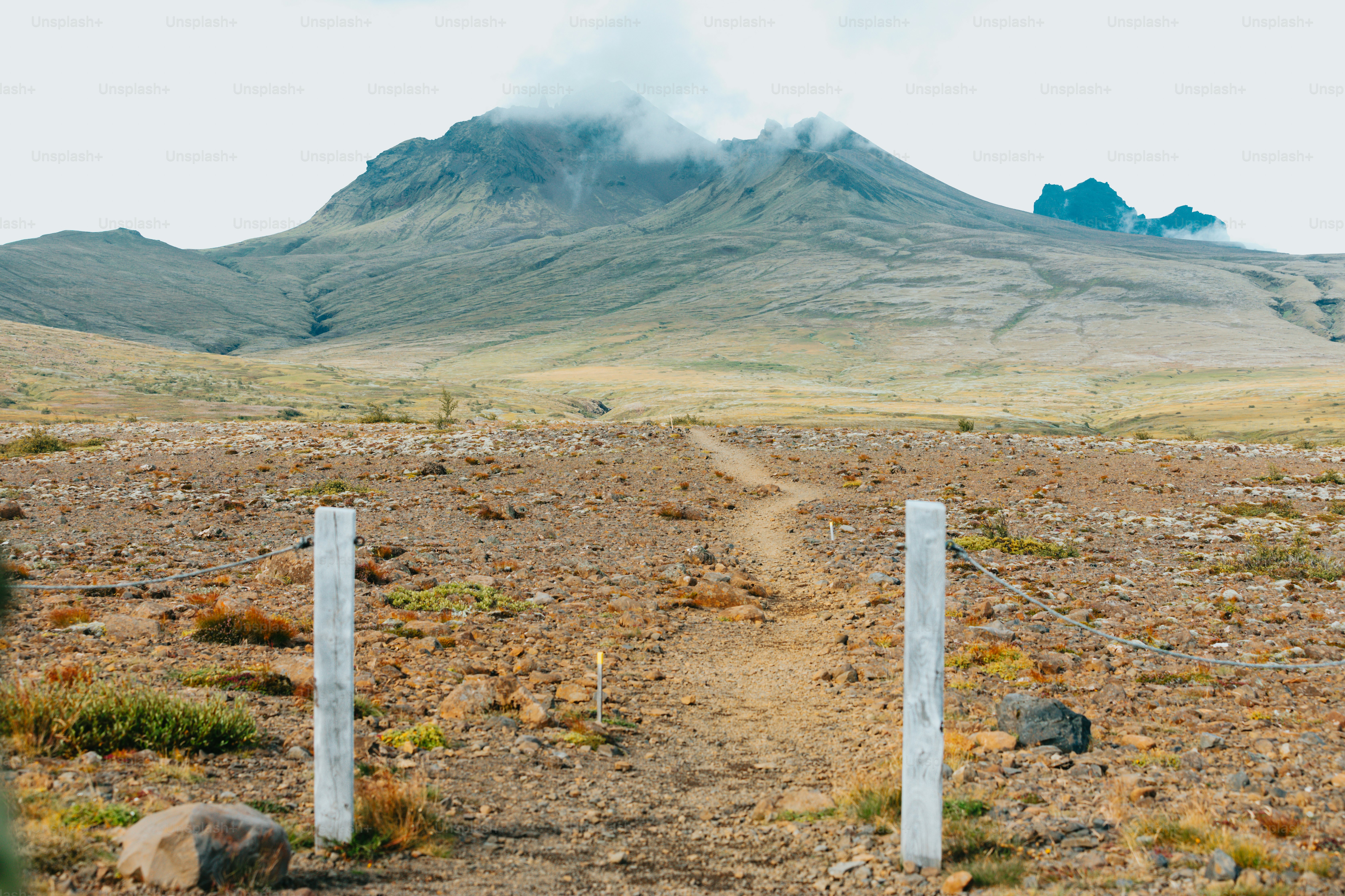 uma estrada de terra com uma montanha ao fundo