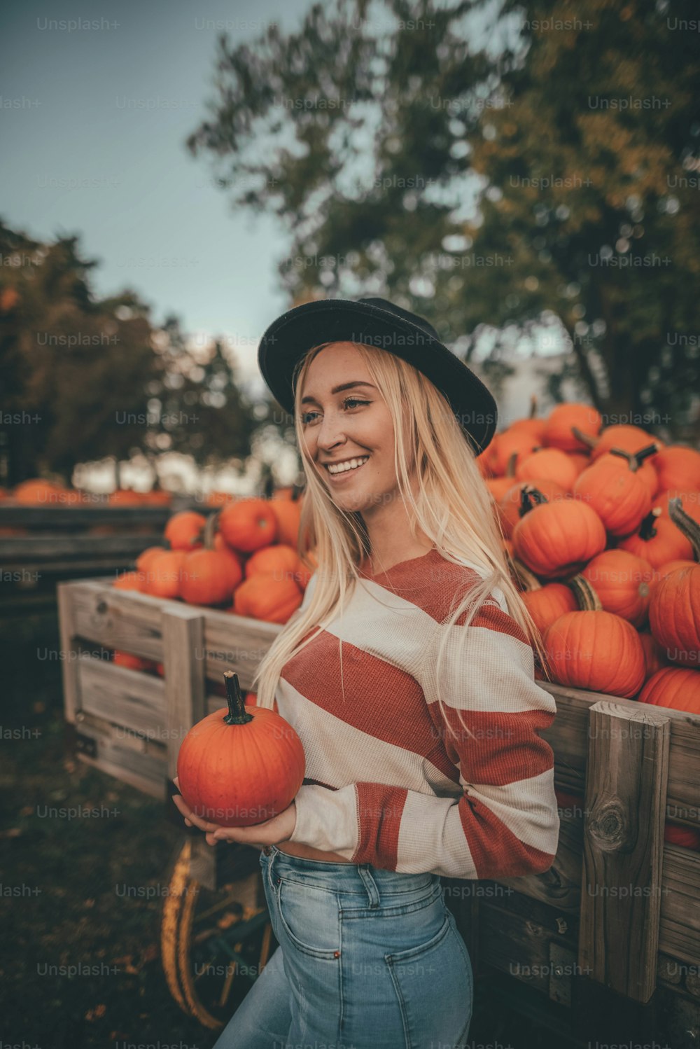 a woman standing in front of a truck full of pumpkins