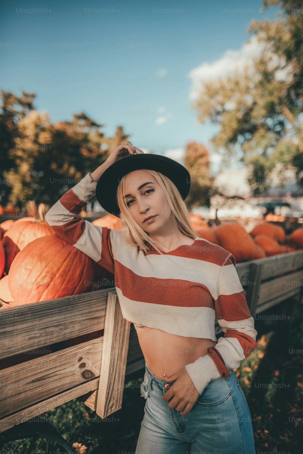 a woman standing next to a pile of pumpkins