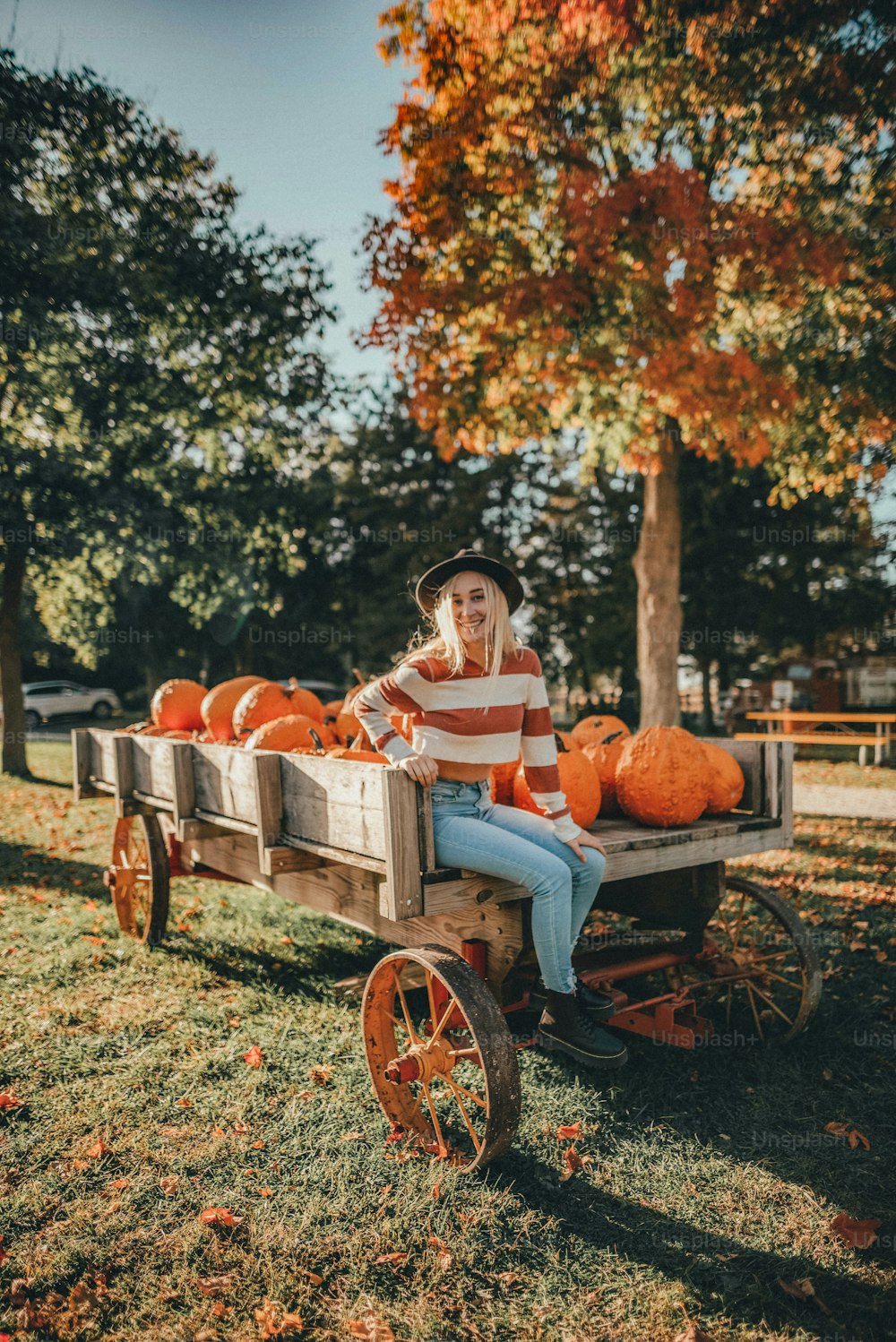 a woman sitting in a wagon filled with pumpkins