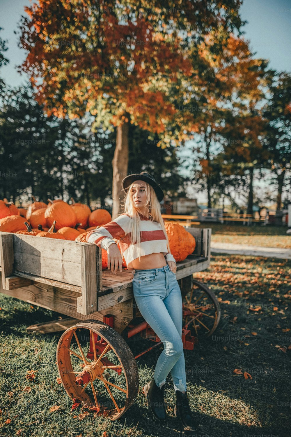 a woman sitting on a wagon filled with pumpkins