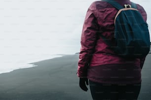 Una persona con uno zaino che cammina su una spiaggia
