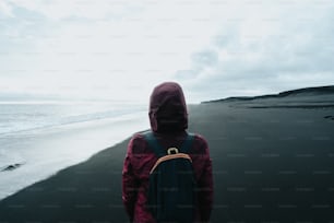 a person with a backpack walking on a beach