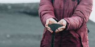 a person holding a handful of dirt in their hands