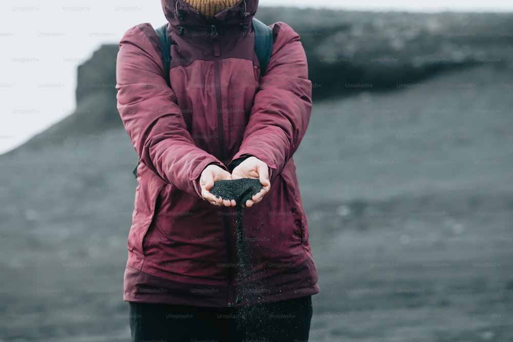 a woman in a purple jacket holding a black object