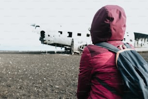 a person with a backpack looking at an airplane