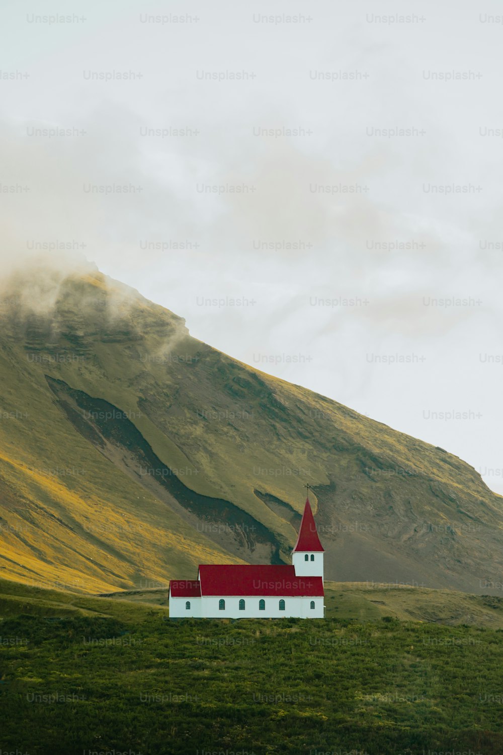 Una iglesia roja y blanca en una colina verde