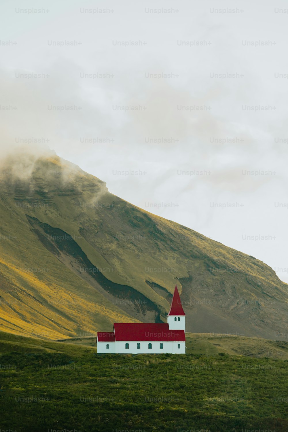 a red and white church on a green hill