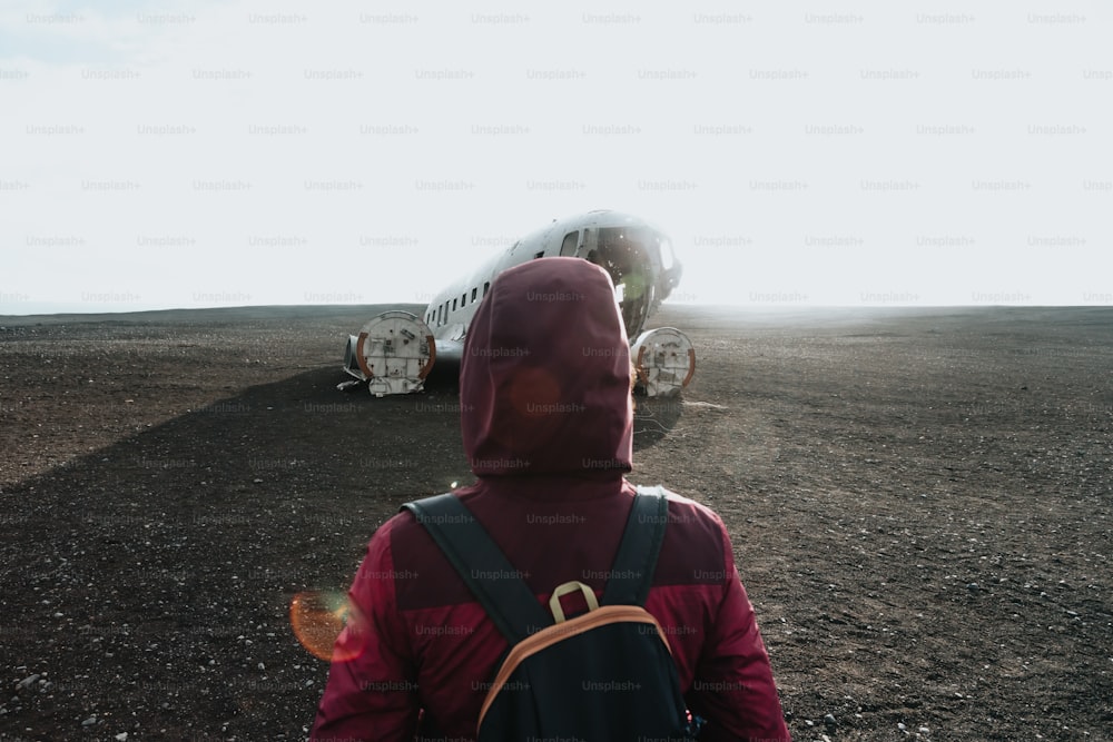 Una persona con uno zaino sta guardando un aereo