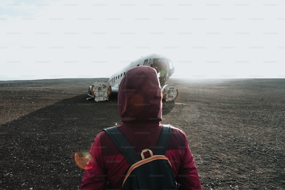a person with a backpack is looking at a plane