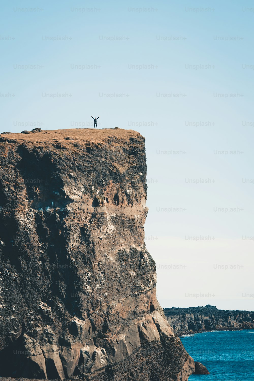 Una persona in piedi sulla cima di una scogliera vicino all'oceano