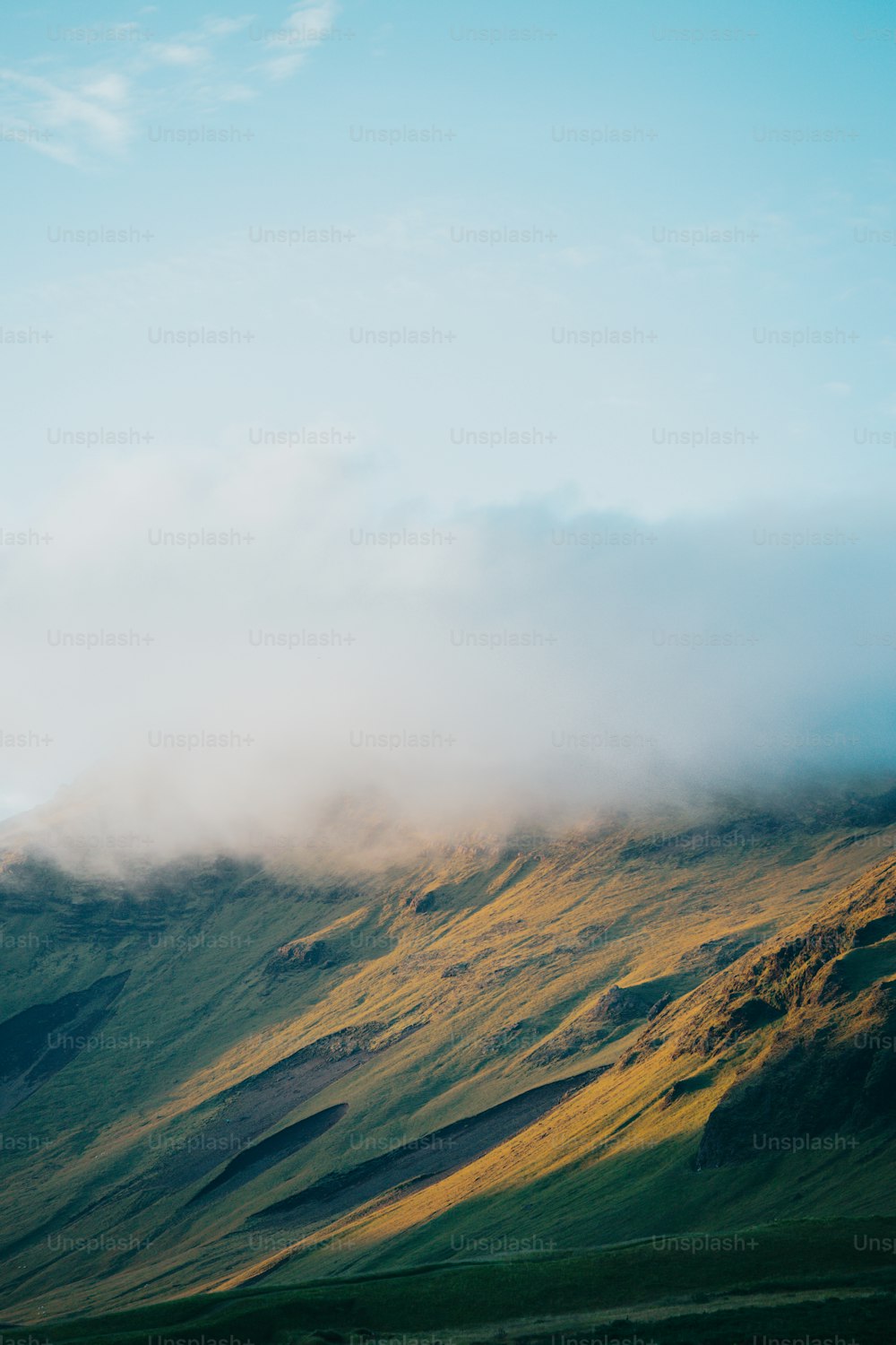 Une montagne couverte de brouillard et de nuages par une journée ensoleillée