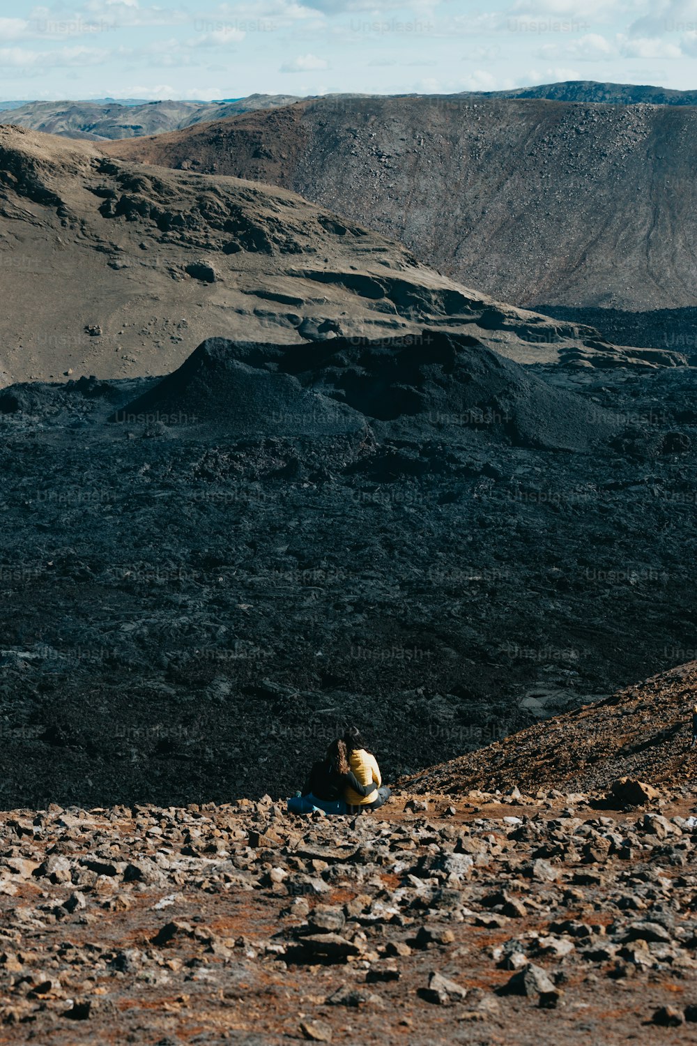 Una persona sentada en la cima de una colina rocosa