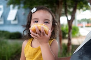 a little girl is eating a donut outside
