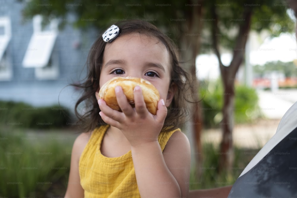 uma garotinha está comendo uma rosquinha do lado de fora